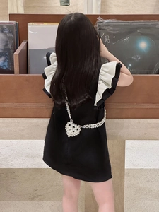 Détail d'une robe noire pour fille avec manches volantées et sac cœur en perles