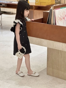 Elegant girl in black dress with white ruffles, pearl accents, and stylish handbag