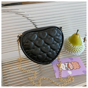 Detail of heart-shaped quilted texture on black crossbody bag with gold chain strap