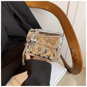 Detail of silver laser mirror finish crossbody bag with camellia flower and quilted pattern