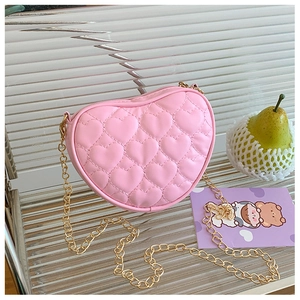 Close-up of pink heart-shaped quilted shoulder bag with gold chain strap and metal zipper