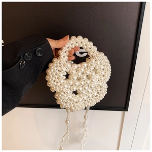 Detail of elegant white faux pearl handbag with flowing tassel fringes and woven texture