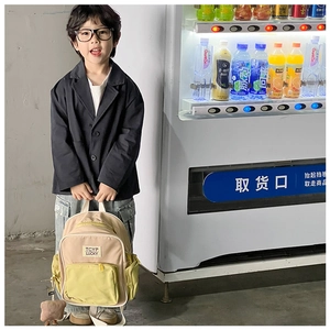 Detail view of kids color-block backpack with logo patch and plush charm held by a child