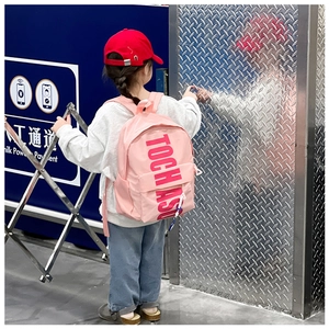 Pink kids backpack with TOCH ASU lettering shown in a stylish urban street style setting