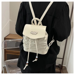 Detail eines weißen Mini-Lederrucksacks mit Kordelzug und modischer Metallplatte