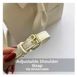 Detail of adjustable PU leather shoulder strap with gold-tone buckle on cream bag