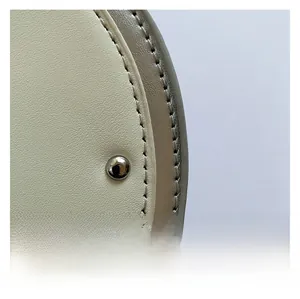 Close-up of fine stitching and silver rivet on cream-colored faux leather guitar bag