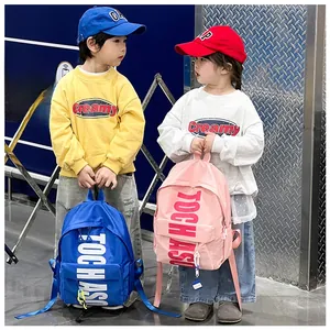 Outdoor street style shot of kids wearing high-capacity backpacks with bold letter prints