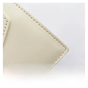 Detail of cream PU leather with pebbled texture and neat stitching on a crossbody bag