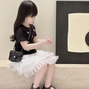 Girl in black bow T-shirt and white tutu with a quilted patent chain crossbody bag