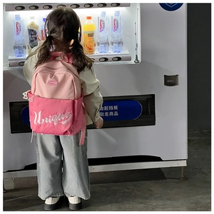 Detailed back view of a pink school bag with Unique print on a child's shoulder