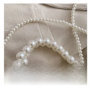 Détail macro d'un sac à main en perles blanches tissées avec anneaux métalliques argentés