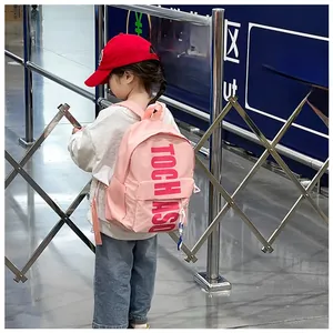 Rear view of a child wearing a pink nylon waterproof school bag with letter prints