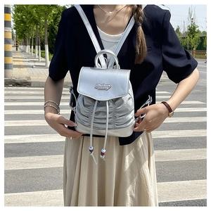 Detail of silver metallic textured backpack featuring elegant pleats and brand logo