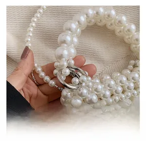 Vue macro de perles crème tissées avec un crochet en métal argenté sur un sac à main
