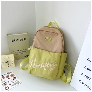 Detailed view of the 'Unique' embroidery on the camel and green water-resistant canvas bag