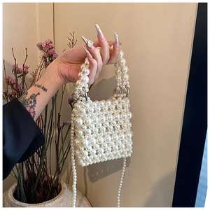 Detail of handmade pearl beaded mini bag with twin top handles and crossbody strap