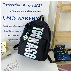 Close-up of black backpack featuring holographic TOCHASO letters and green m-letter charm