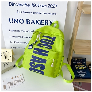 Detail of neon green kids backpack with blue TOCHASO lettering and white zipper pullers