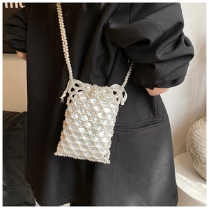 Detail of elegant pearl woven mini crossbody bag with drawstring liner and long shoulder strap