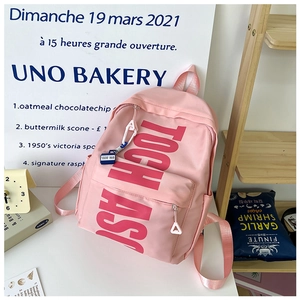 Detailed side view of pink school backpack with stylish letter print and decorative charms
