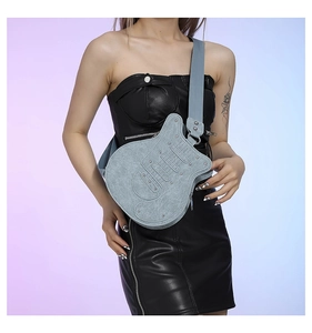 Detail of light blue guitar-shaped denim crossbody bag with silver rivets and wide strap