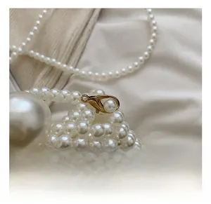 Detail of premium golden lobster clasp and white pearl woven texture on a handbag