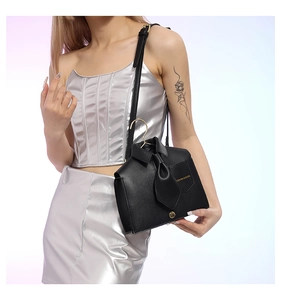 Detail of unique shirt-shaped black leather shoulder bag with miniature tie and metal hook