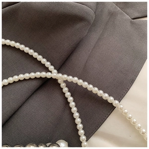 Detail shot of lustrous white pearl strap with premium metallic texture for kids bag