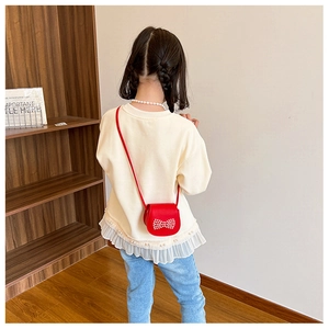 Détail du mini sac bandoulière rouge pour enfants avec un délicat nœud en perles blanches