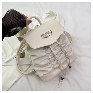 Detail of off-white backpack featuring pleated drawstring design and metallic fashion badge