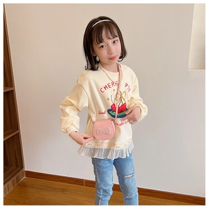 Détail d'un sac rose pour fille avec nœud en perles et sweatshirt assorti aux cerises
