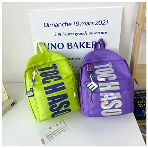 Detail of neon green and purple student backpacks with large TOCHASO letter printing