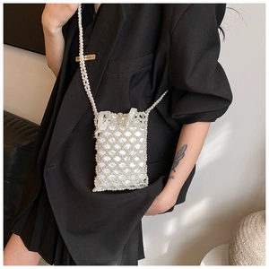 Detail of white pearl woven crossbody bag with satin lining worn on black suit