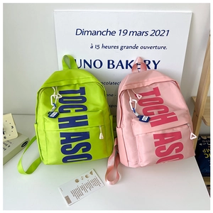 Detail of neon green and pink backpacks with bold TOCH ASO letter prints and zip pockets