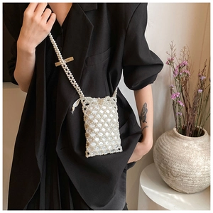 Chic handcrafted pearl crossbody bag with hollow lattice design on black blazer outfit