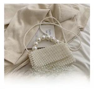 Detail show of white woven pearl handbag with elegant top handle and crossbody strap