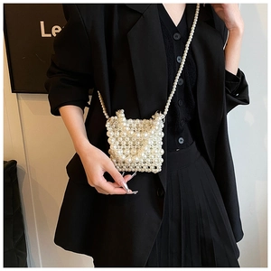 Detail shot of a handmade white pearl woven crossbody bag on a model in a black outfit