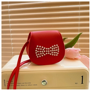 Détail du sac bandoulière rouge pour enfant avec nœud en perles et texture en cuir PU