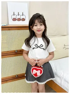 Girl's white T-shirt with bow and pleated skirt with lace hem and red heart bag