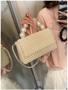 Detail of hand-woven white pearl handbag featuring large pearl handle and shoulder strap