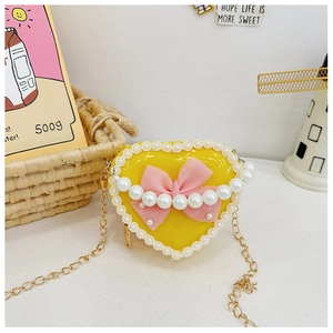 Detail of yellow heart kids purse with pink bow, pearl accent and lace edge