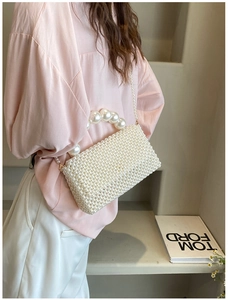 Close-up of handmade woven pearl handbag with top handle and delicate shoulder strap