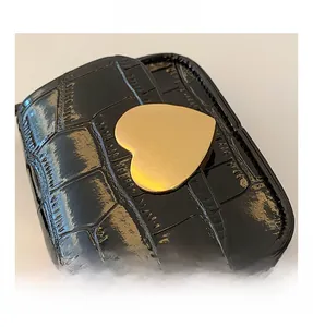 Detailaufnahme einer schwarzen Krokostruktur-Tasche mit großer goldener Herzschnalle