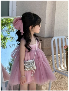 Detail of pink tiered mesh girl dress featuring a large tulle bow on the back and pearls