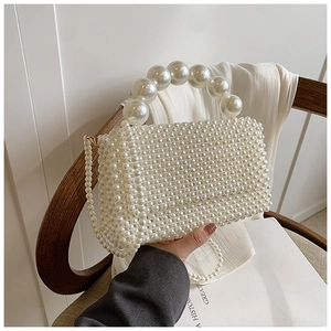 Macro detail of hand-woven pearl handbag with large decorative pearl handle and chain