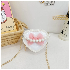 Detail of white heart-shaped kids crossbody bag with pink bow and pearl accent