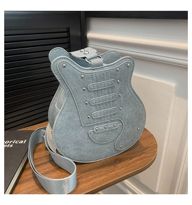 Detailed view of guitar-shaped bag showing light blue suede texture and silver metal rivets