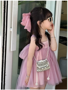 Pink tulle princess dress styled with a matching bow headpiece and pearl crossbody bag