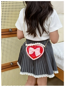 Detail of red heart girl's handbag with lace trim, pearl handle, and mesh bow accessory